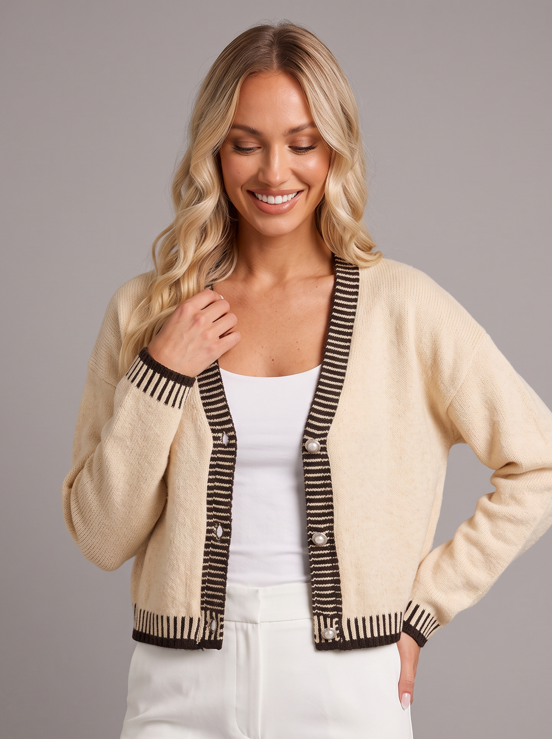 Woman wearing an apricot cropped V-neck cardigan with contrast trim