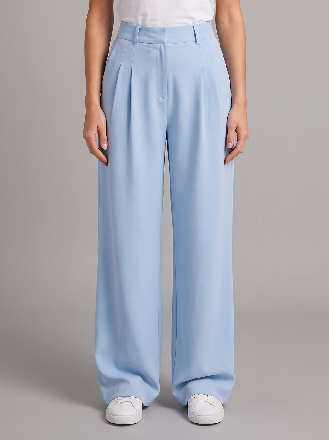 Woman wearing sky blue high-waist pleated wide leg trousers, front view