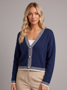 Woman wearing a navy cropped V-neck cardigan with striped trim