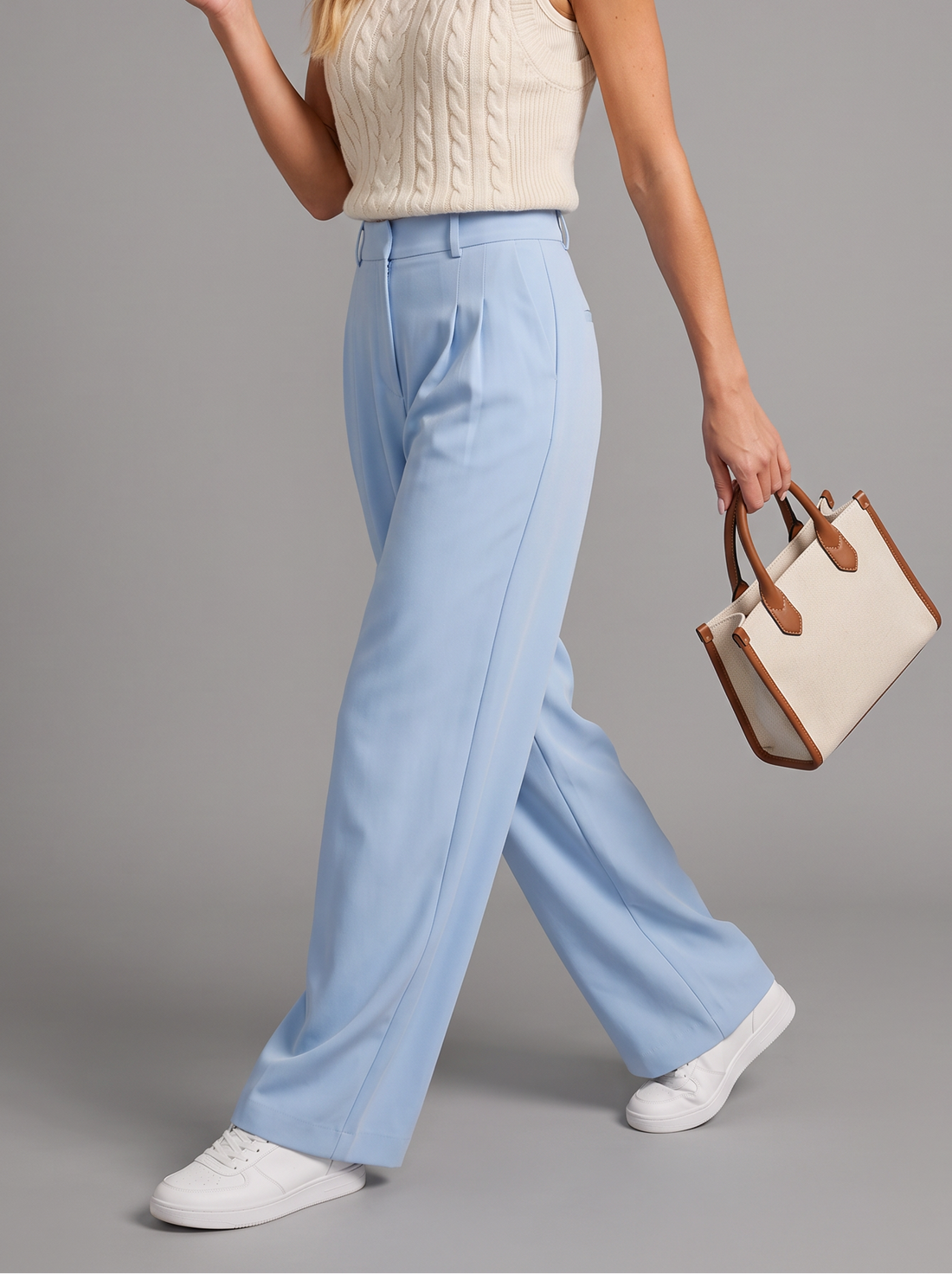 Woman walking in sky blue wide leg trousers with a tote bag