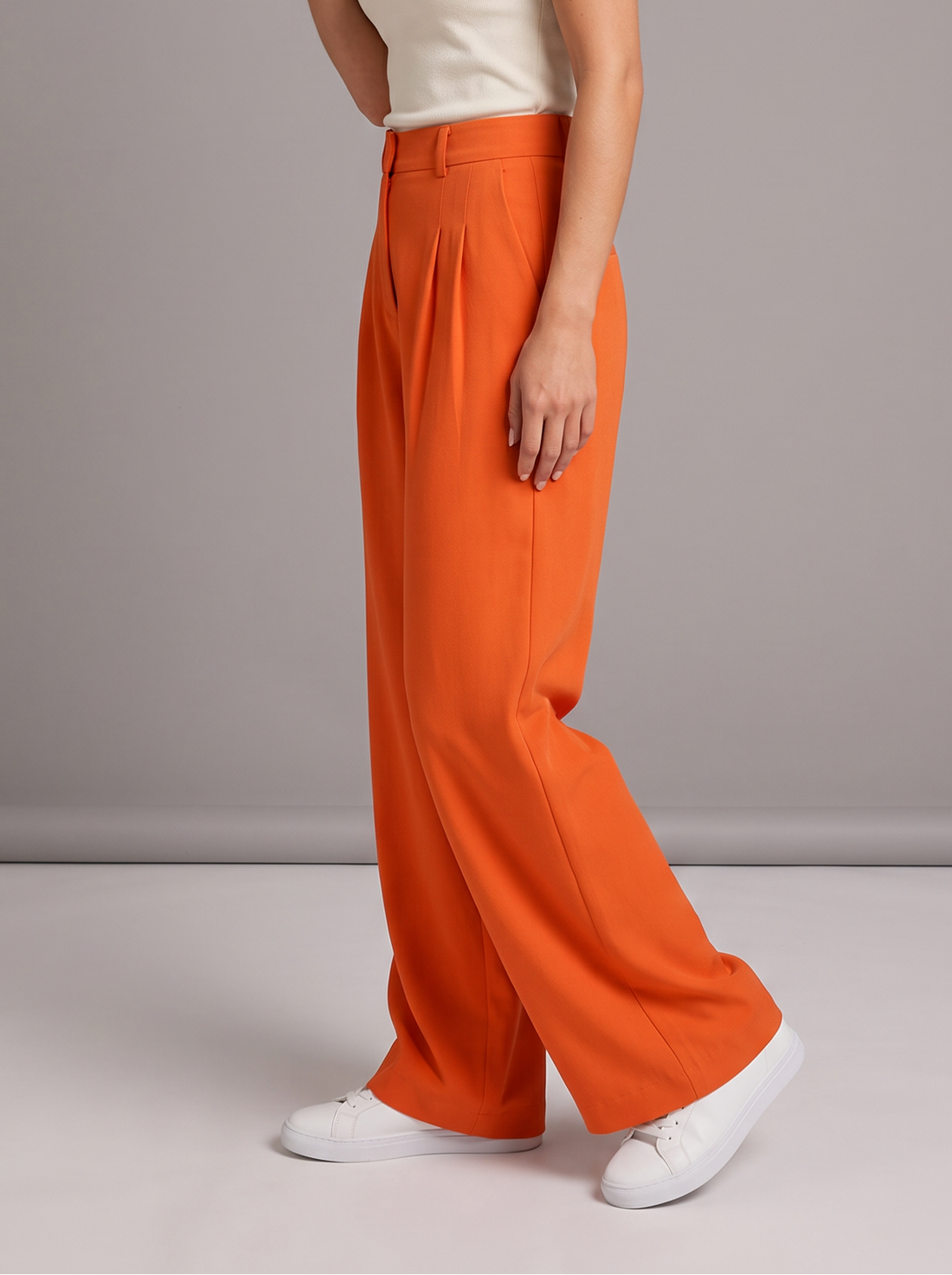 Woman wearing orange pleated wide leg trousers