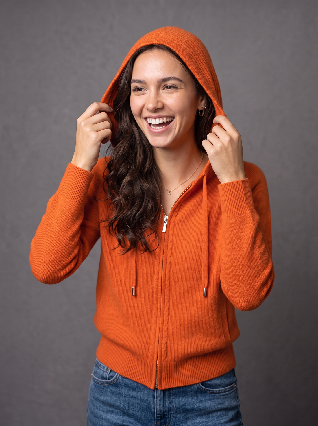 Woman laughing in orange knit zip hoodie cardigan with hood up