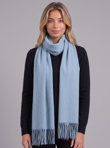 Woman wearing light blue tassel wrap scarf