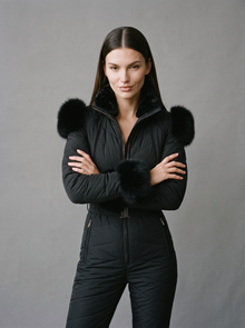 Woman wearing black quilted one-piece ski suit with fur trim