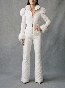 Woman wearing white quilted one-piece ski suit with fur trim, front view