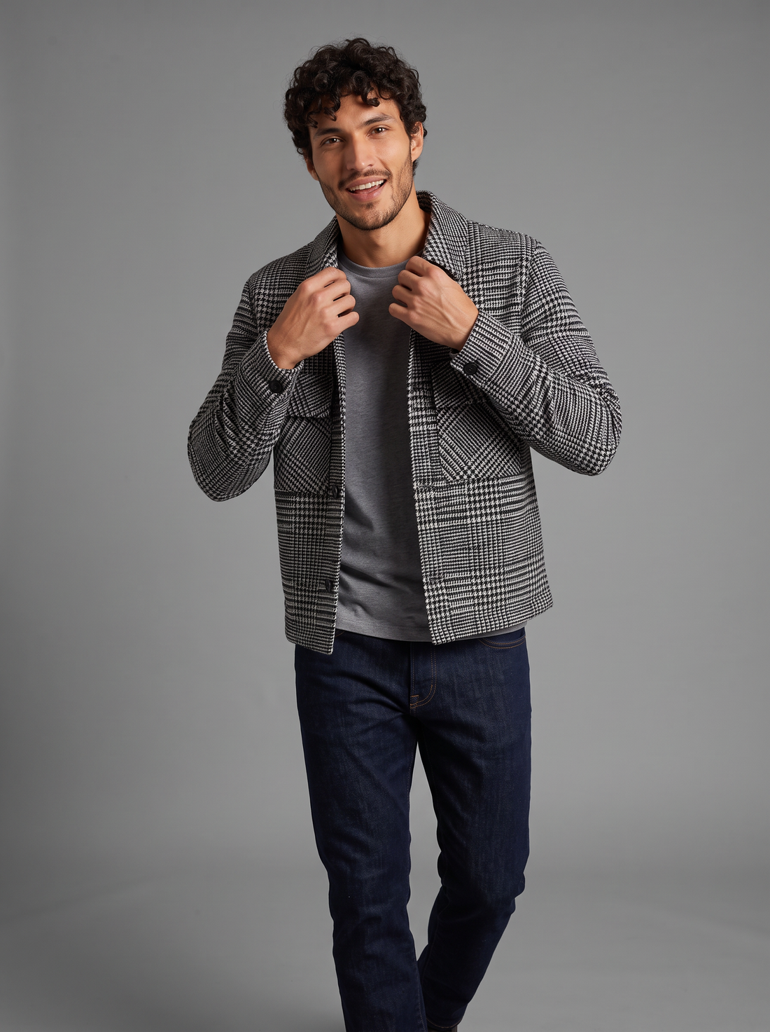 Man walking in open grey houndstooth overshirt jacket with jeans