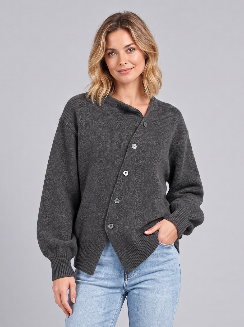 Woman wearing a grey cashmere knit jumper with asymmetric button front and light blue jeans