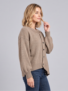Side view of a brown cashmere button-front jumper worn with dark jeans
