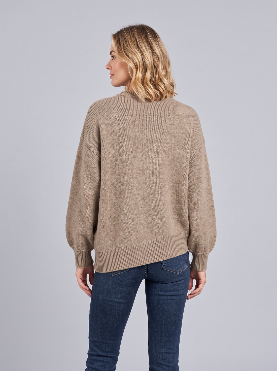 Woman wearing a brown cashmere knit jumper with asymmetric diagonal button front and balloon sleeves, front view