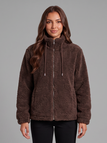 Woman wearing a dark brown teddy fleece zip jacket with black quilted snow boots, front view