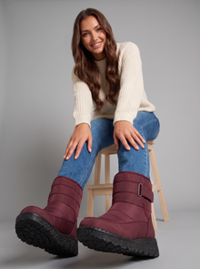 Woman seated on a stool showing burgundy quilted snow boots
