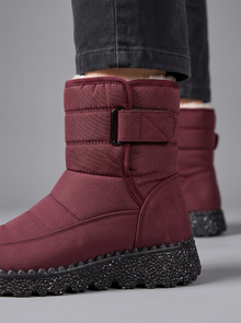 Close-up of burgundy quilted snow boot showing velcro strap and chunky speckled sole