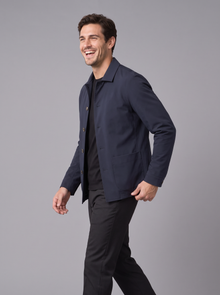 Man laughing and walking in a navy button-up shirt jacket, side view