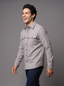 Man walking in a light grey button-up overshirt, side view