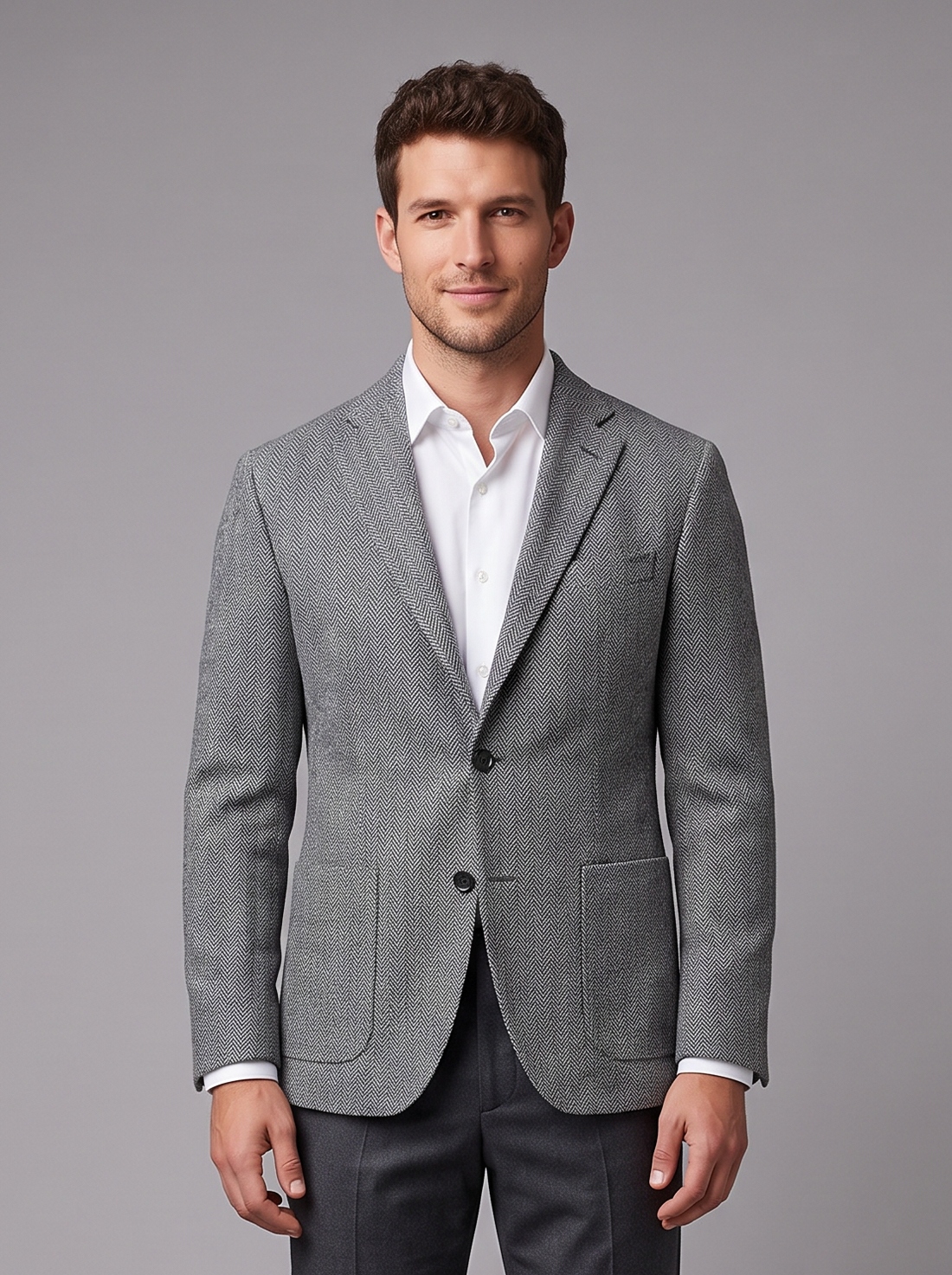 Man in a grey herringbone tweed single-breasted blazer with charcoal trousers, full-length front view